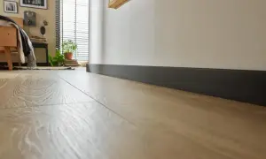 Nowoczesne, ciemne cokoły podkreślają jasną podłogę w sypialni.