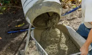 Świeża porcja betonu z betoniarki trafia do taczki, gotowa do budowy fundamentów.
