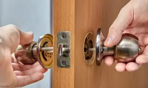 Instrukcja krok po kroku, jak wymienić zamek w drzwiach. Dłonie demontują klamkę i mechanizm zamka.