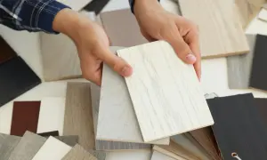 Ręce trzymają próbki materiałów, w tym jasne płyty z widocznym usłojeniem, przypominające MDF. Wybór idealnego wykończenia.