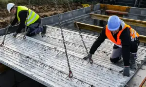 Dwóch budowlańców przygotowuje strop filigran do montażu.