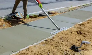 Robotnik wygładza świeży beton na chodniku, tworząc solidną klasę betonu.