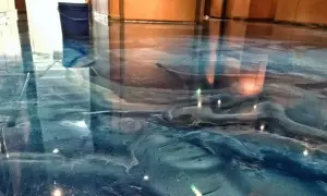 Błękitna żywica posadzkowa z efektem fal, przypominająca morskie głębiny. W tle niebieskie wiadro.