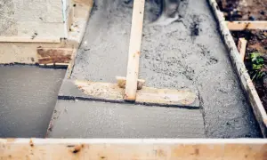 Praca z betonem: cement, piasek i woda tworzą tę masę, którą wyrównuje się drewnianą łopatą w szalunku.