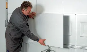 Mężczyzna montuje panel do ocieplenia bramy garażowej.