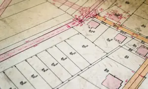 Stary plan geodezyjny z zaznaczonymi budynkami i numerami działek ewidencyjnych.