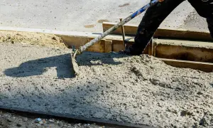 Pracownik rozprowadza świeży beton c30/37 za pomocą łopaty.
