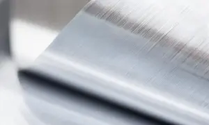 Szczotkowana powierzchnia metalu po procesie anodowania, z widocznymi równoległymi liniami.