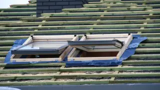 Dach prefabrykowany w budowie, z widocznymi oknami dachowymi i drewnianą konstrukcją.