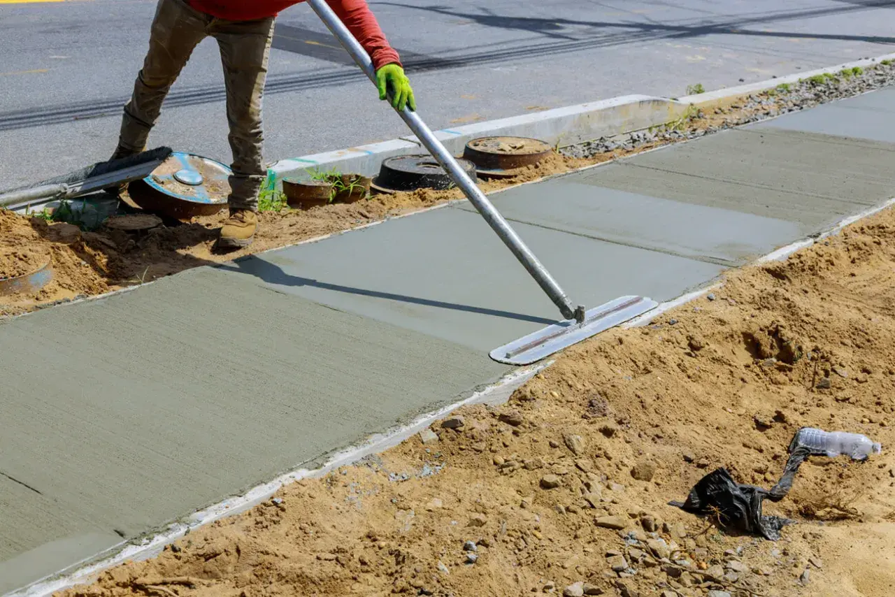 Robotnik wygładza świeży beton na chodniku, tworząc solidną klasę betonu.