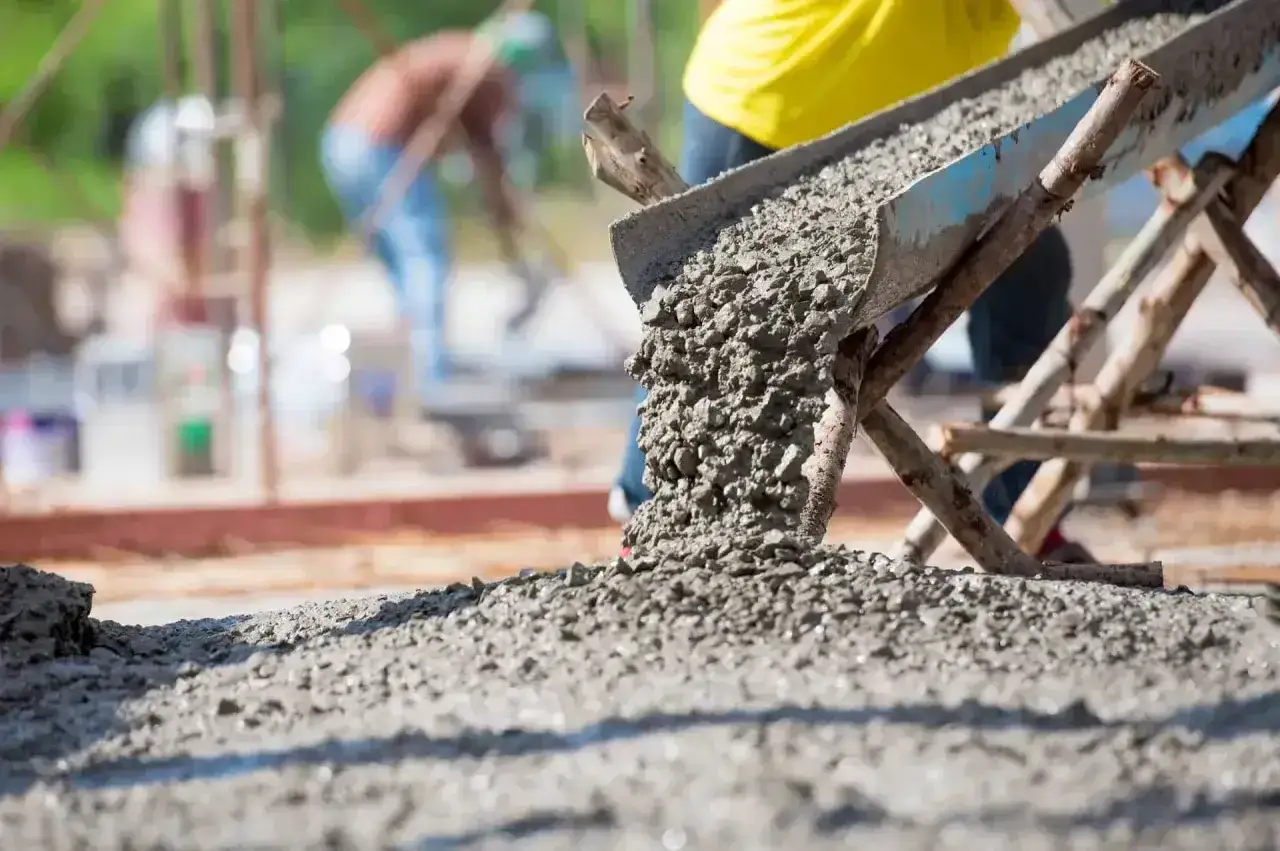 Beton wylewany z rynny na placu budowy. Waga 1m3 betonu suchego jest kluczowa dla obliczeń.