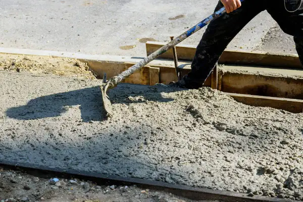 Pracownik rozprowadza świeży beton c30/37 za pomocą łopaty.